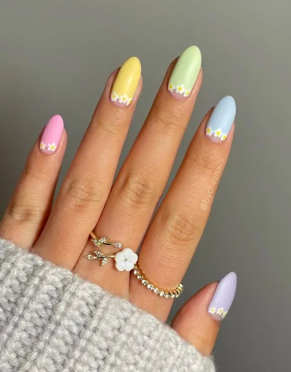 Pastel acrylic nails featuring small white daisy flowers with yellow centers.
