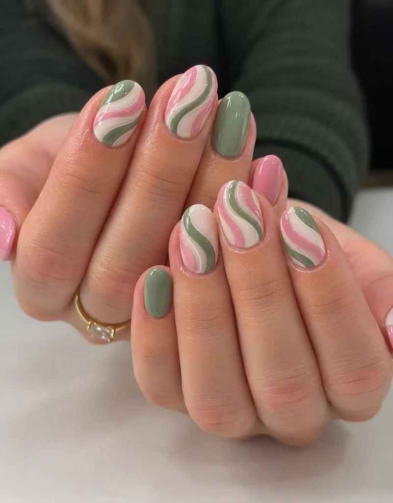 Pink and green Christmas swirl nails with flowing curved lines over a milky base