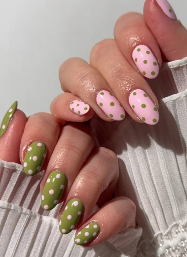 Pink and green Christmas polka dot nails with evenly spaced contrasting dots on colored bases