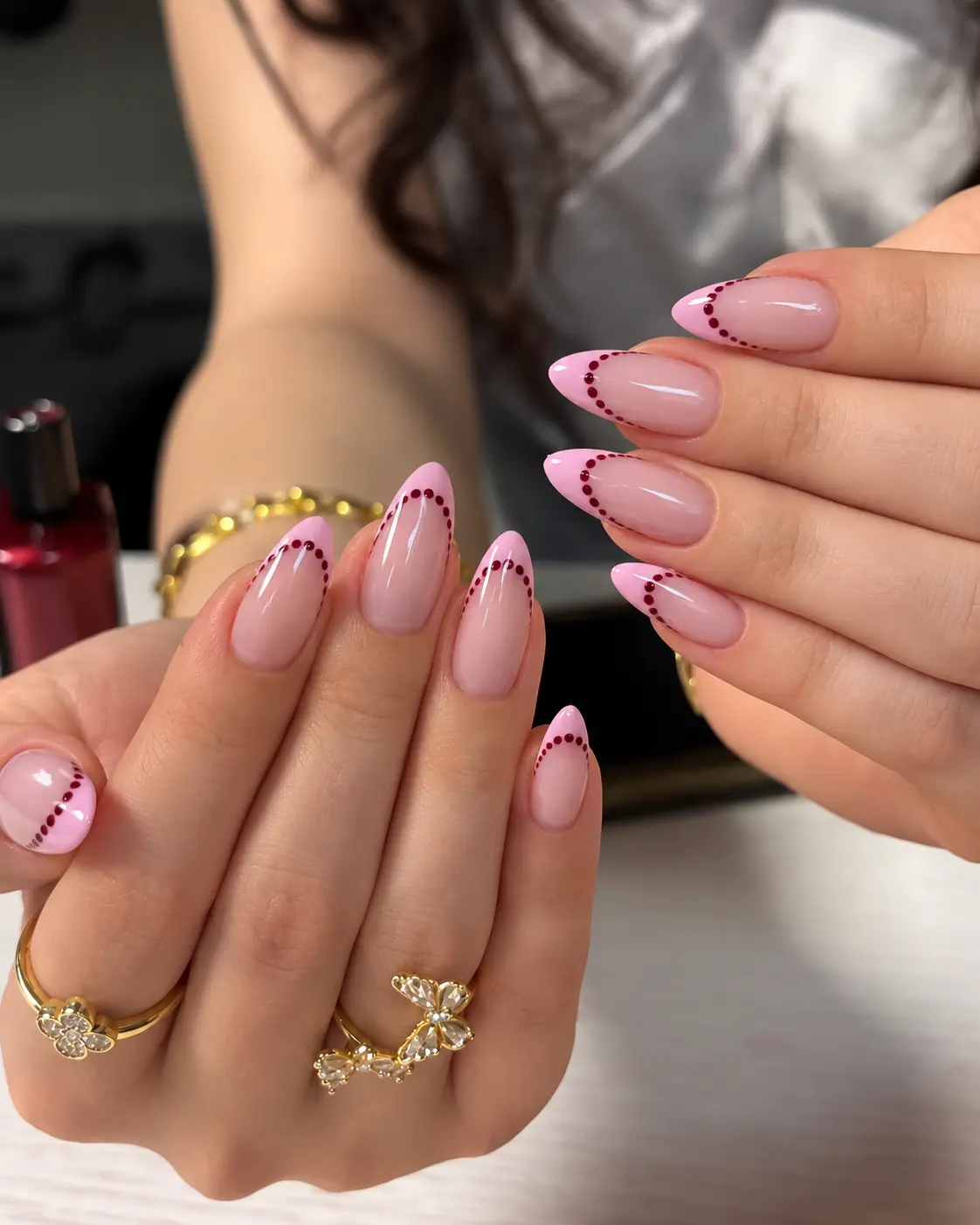 Pink French tip nails decorated with burgundy dots along the tips