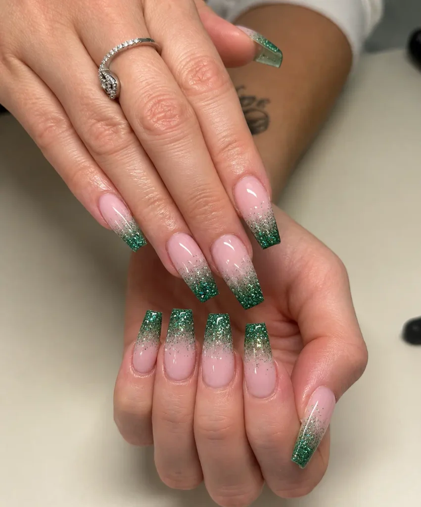 Pink Christmas nails with emerald green glitter fading from the tips into a rosy pink base