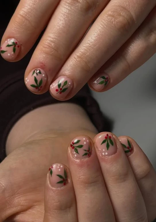 Pink Christmas nails decorated with green holly leaves and bright red berry clusters