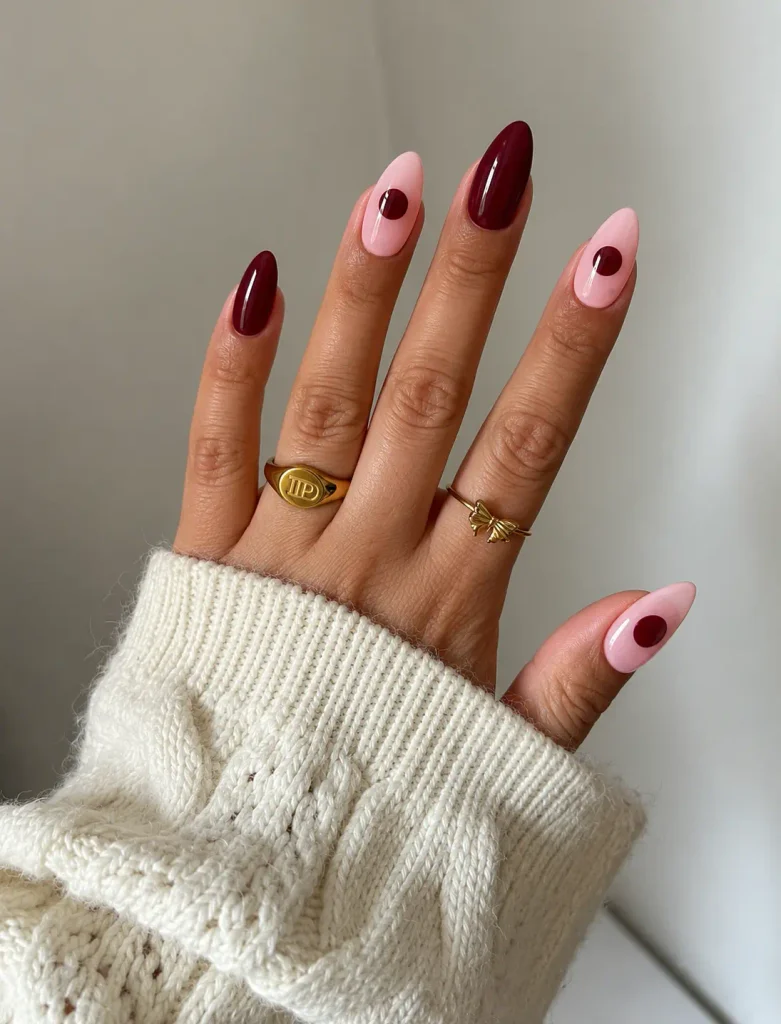 Pink nails featuring one large burgundy polka dot on each nail