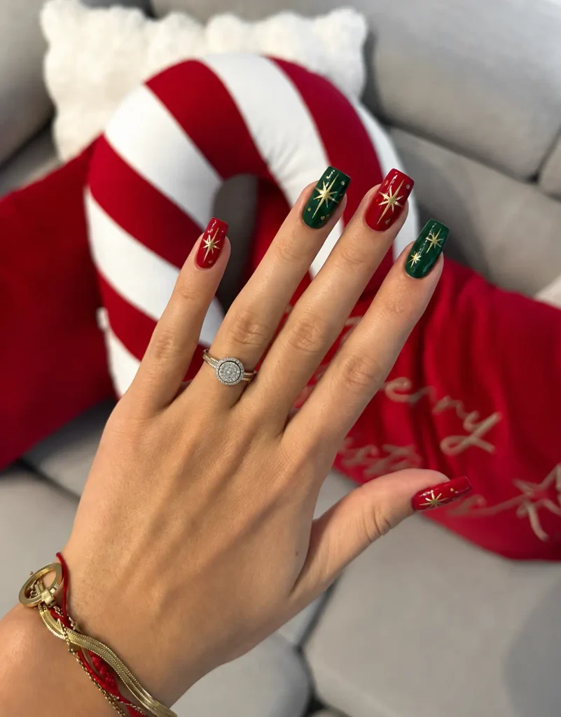 Red and green Christmas nails with delicate gold starburst nail art on solid-color polish