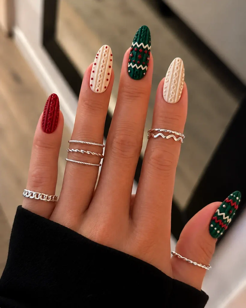 Red and green Christmas sweater nails with knitted diamonds, zigzags, and textured nail art