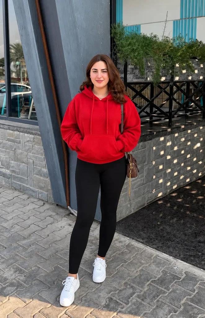 Casual Christmas outfit with a red hoodie, black leggings, and white sneakers for a relaxed holiday look