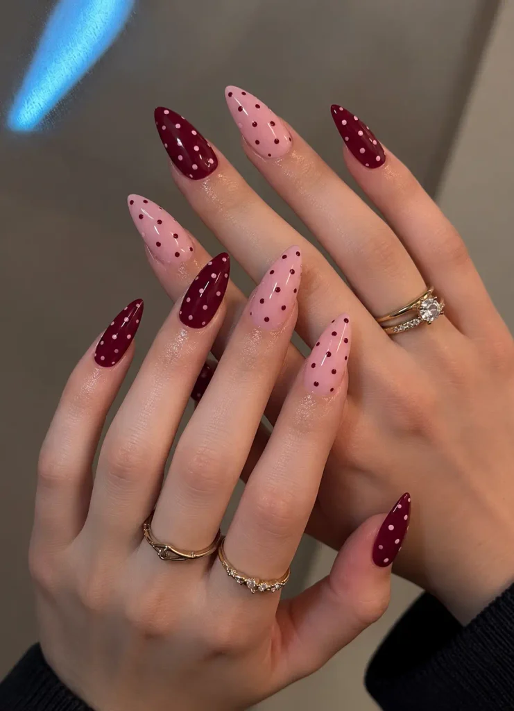 Burgundy and pink nails with burgundy and pink dots scattered across the nail surfaces