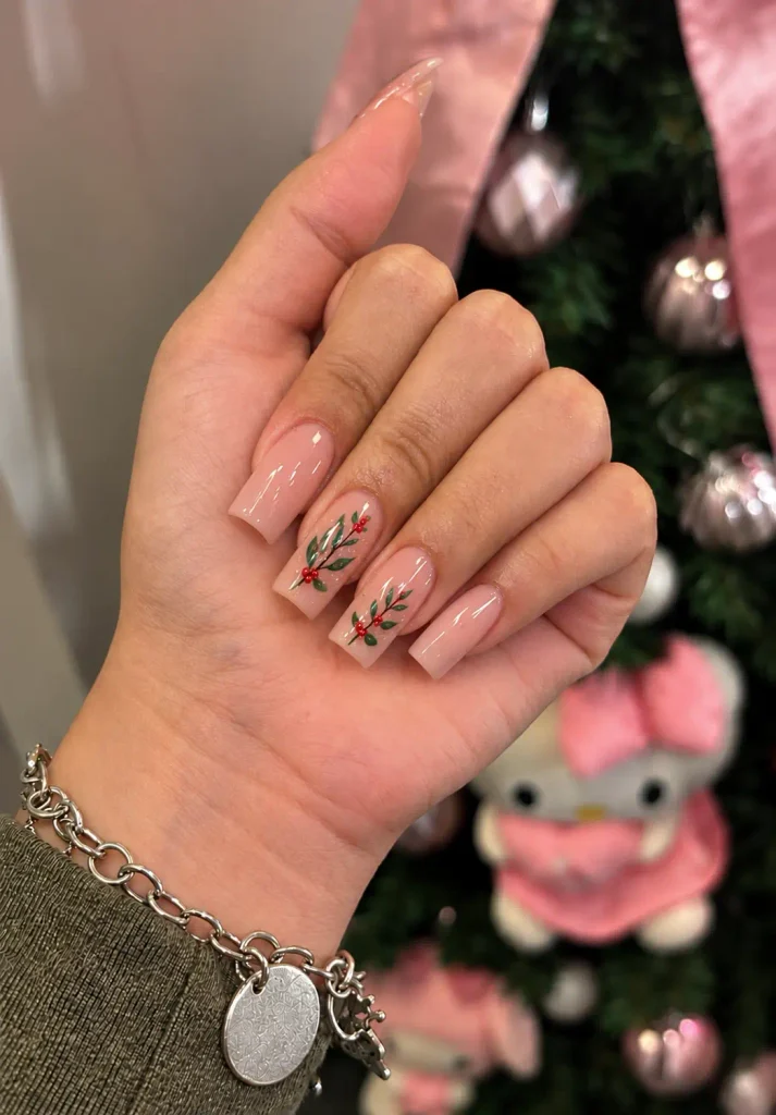 Sheer nude Christmas nails with delicate green mistletoe sprigs, red berries, and tiny gold dots