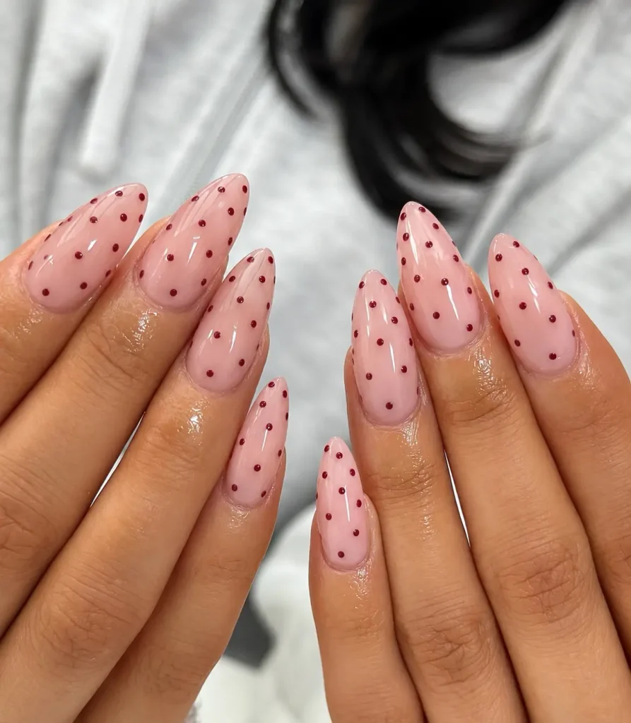 Sheer pink nails decorated with tiny burgundy polka dots